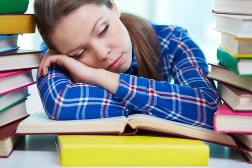 Estudiante cansado durmiendo sobre libros de texto