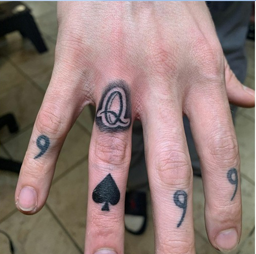 Tatuaje de la letra Q en el dedo anular