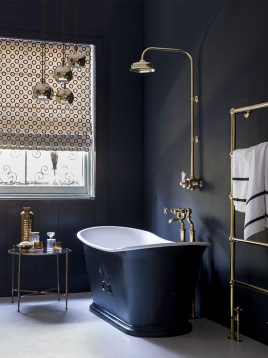 חדר אמבטיה באמבט עצמאי בשחור וזהב באור יום כחול כהה