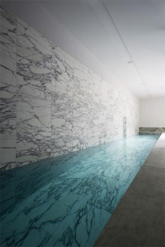 בריכת שחייה מקורה בבית מינימליזם טהור בעיצוב לוחות שיש על הקיר בצבע אפור