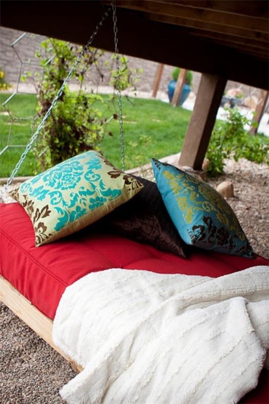 מיטה תלויה בחוץ עם כריות צבעוניות כגן קישוט ירוק ברקע
