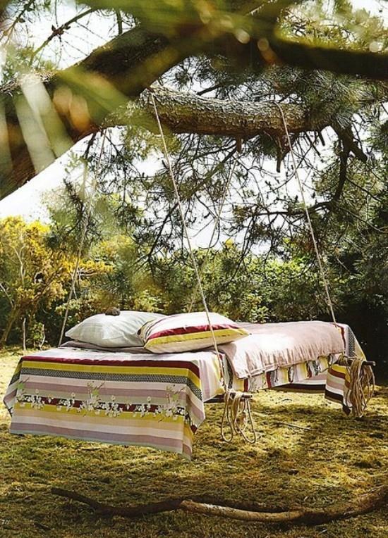 מיטה תלויה בחוץ בגינה על עץ בסגנון בוהו נראית מזמינה