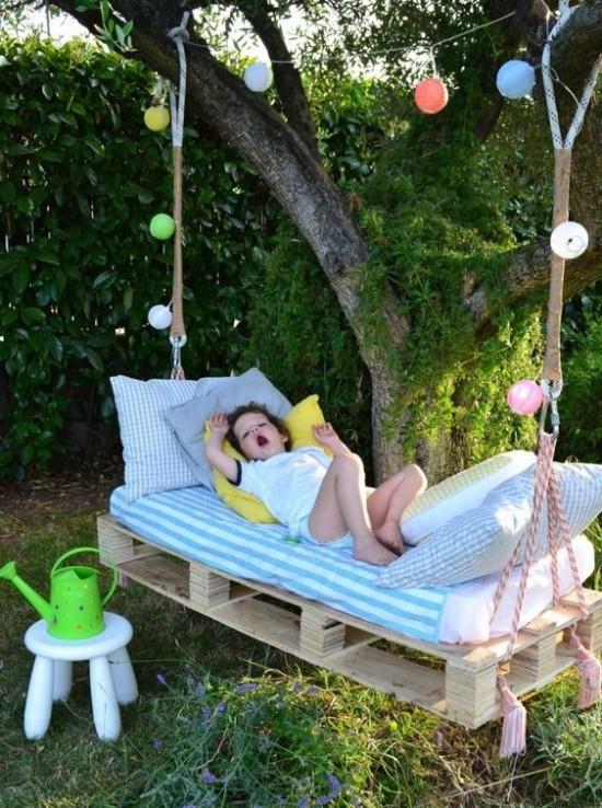 מיטה תלויה בחוץ בגינה ילד מנמנם עליה