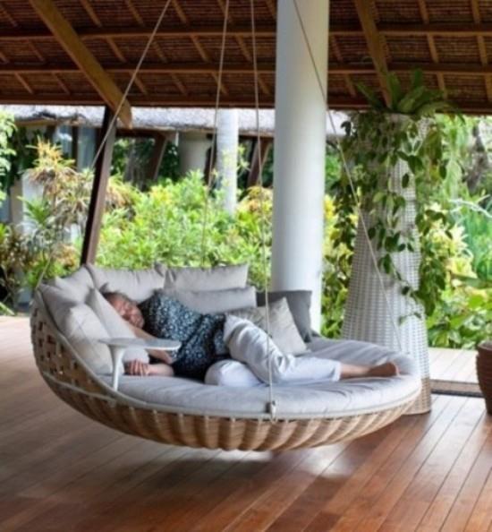 מיטה תלויה בחוץ בצורה עגולה על המרפסת המקורה לתנומת אחר הצהריים בחוץ