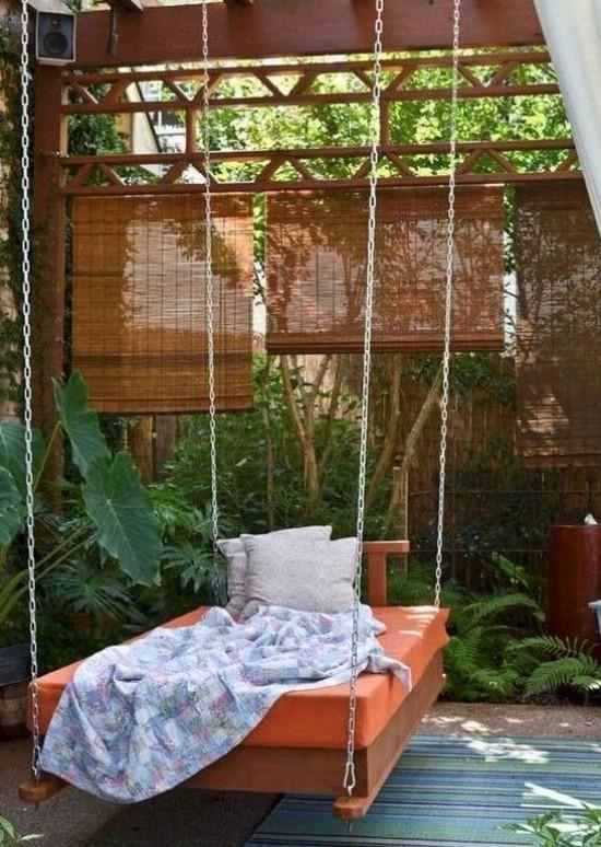 מיטה תלויה בחוץ הרבה צמחים אקזוטיים ירוקים מסך פרטיות במרפסת