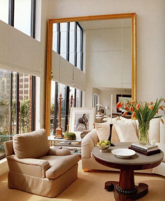 הסלון מרחיב ויזואלית מראה גדולה מדי ליד החלון משקפת את עיצוב החדר ואת האור