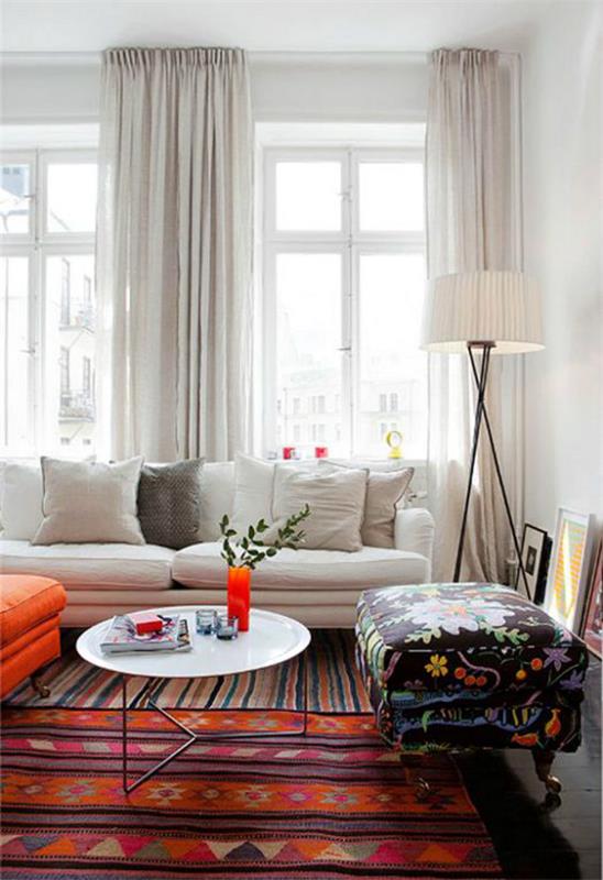 סלון מרחיב אופטית ספה לבנה וילונות לבנים הרבה שטיח צבעוני אור יום שולט