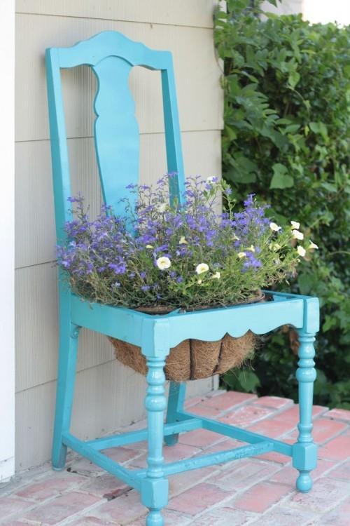 כיסא ישן בעציץ צבוע בכחול באמצע קישוט הגן
