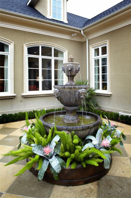 עיטור אקזוטי עם צמחים טרופיים שלושה פרחים ורודים במזרקת המים