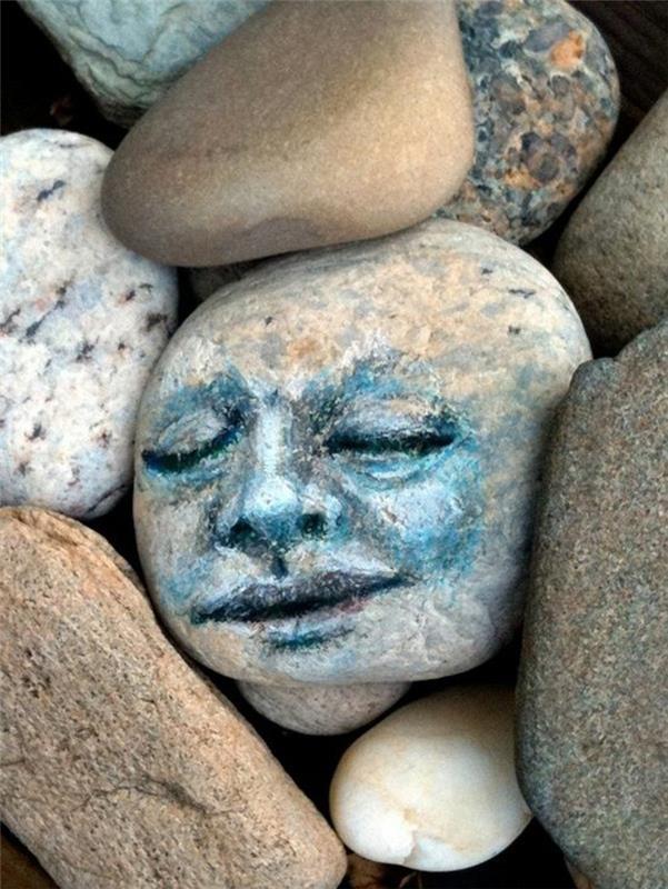 אמנות עם אבנים מציירות פנים על אבן נהר