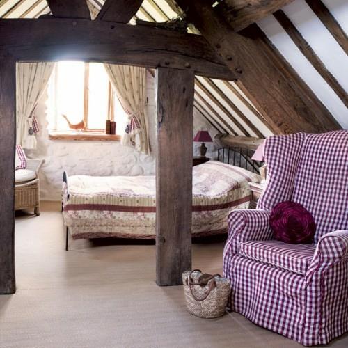 חדר שינה בעליית הגג קורות חשופות ונוחות מעץ כריות