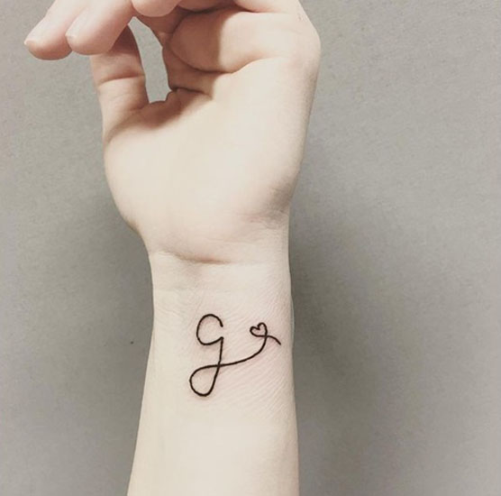 Tatuaggio con lettera G con un cuore sul polso